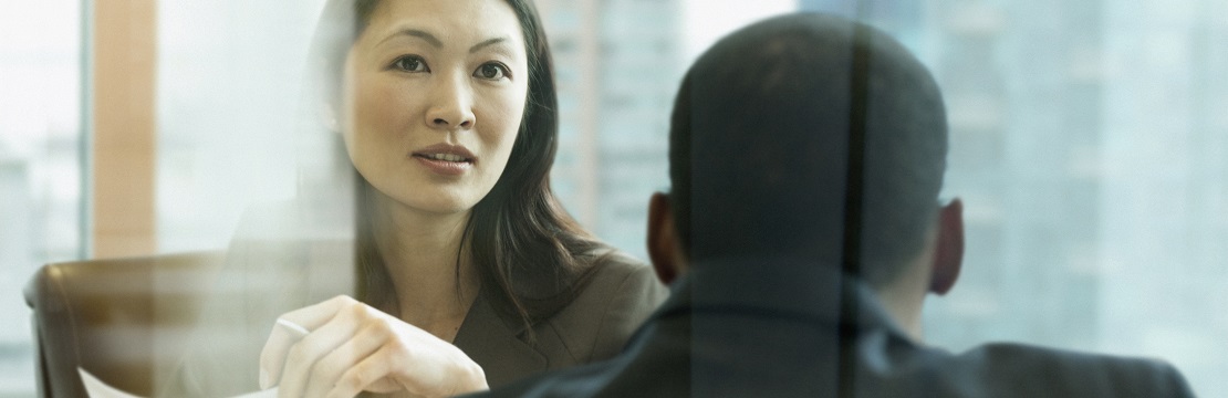 Man and women in professional attire sit across from each other in an office setting