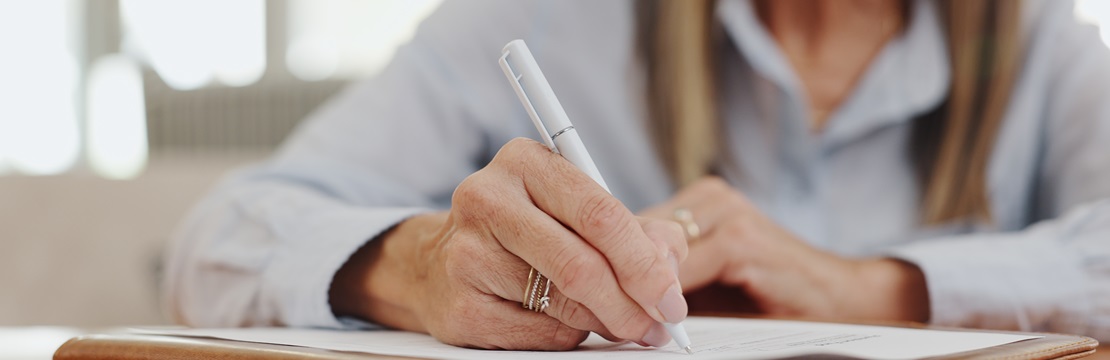 Close-up view of woman writing on a document.
