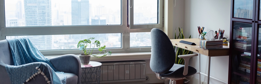 Workspace with a rolling chair and desk with a window view of a cityscape.