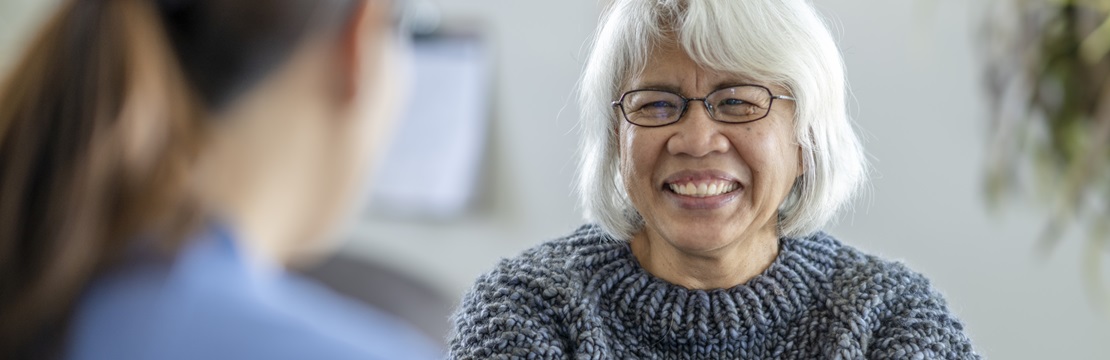 Mature woman smiling at medical professional.